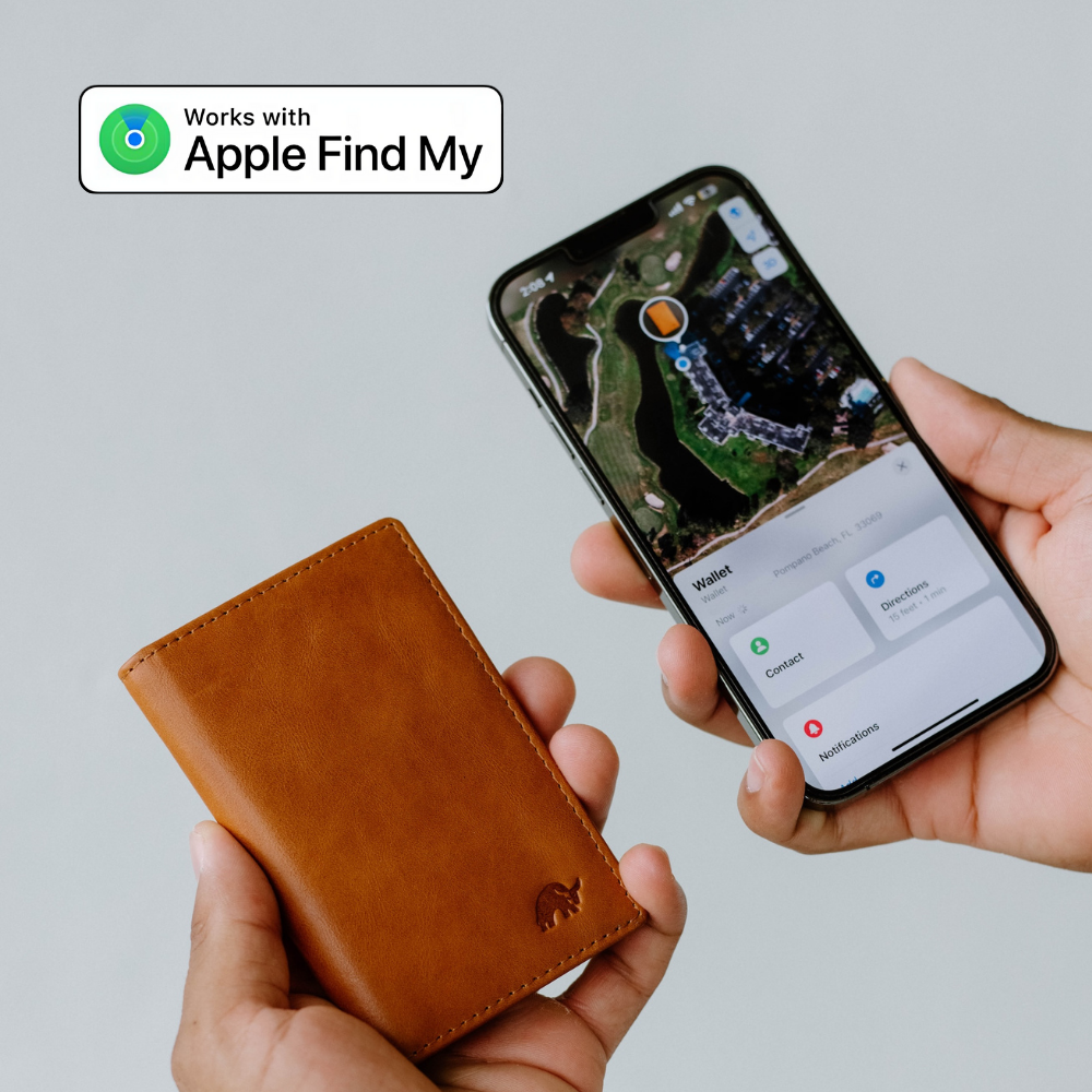 A hand holding a brown wallet next to a phone displaying the Apple Find My app.